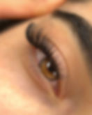 Close-up of full, dark volume eyelash extensions on a brown eye.