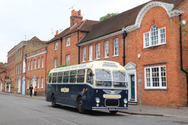 A blue and cream coach by brick buildings
