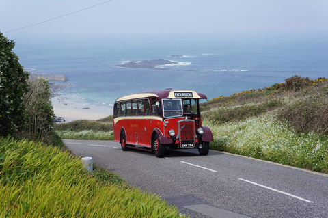 An old red coach on a steep hill with the sea behind