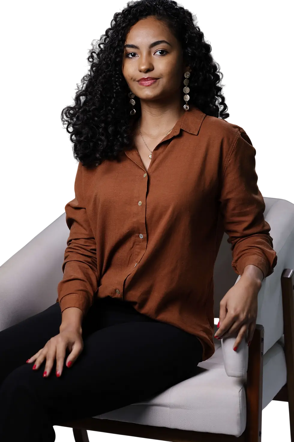 Studio portrait of a woman wearing a rust-colored button-up shirt while sitting in a chair. The lighting is elegant and focused against a dark, minimalist background.