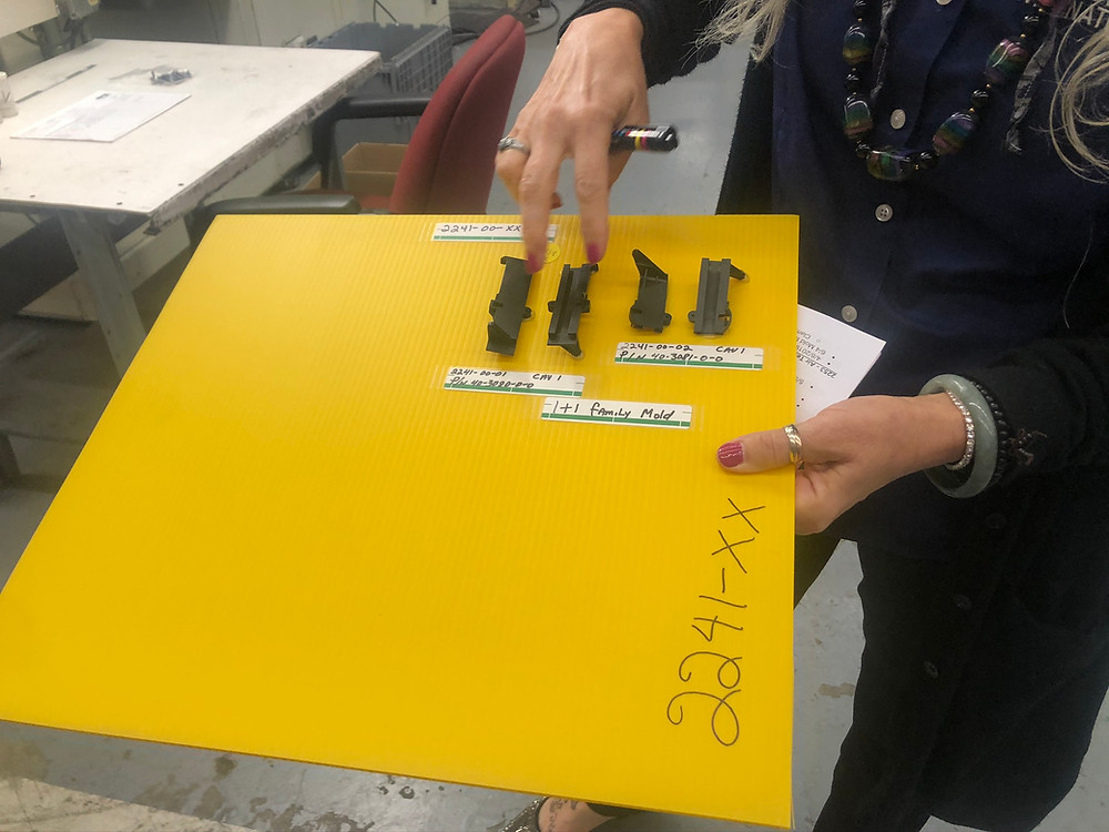A yellow board is being displayed that has various parts made by the manufacturer. There are labels under the parts that show failures and successes.