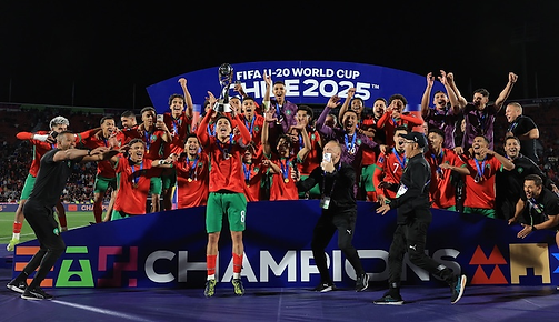 Soccer team in red jerseys celebrates winning a trophy on stage. Banner reads "FIFA U-20 World Cup Chile 2025." Jubilant mood.