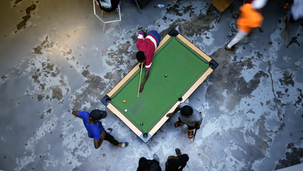 Young people playing pool in a township setting.