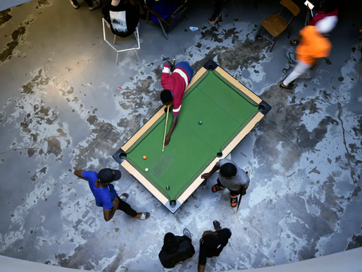 Young people playing pool in a township setting.