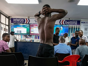 A group of young men outside a betting shop in Harare looking at football odds.