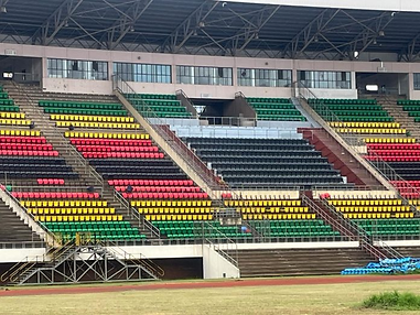 Colorful stadium seats in red, yellow, and green with a few blue chairs near the track. The setting is empty, creating a quiet, orderly mood.
