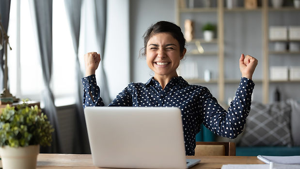 Young woman celebrating success at her laptop.