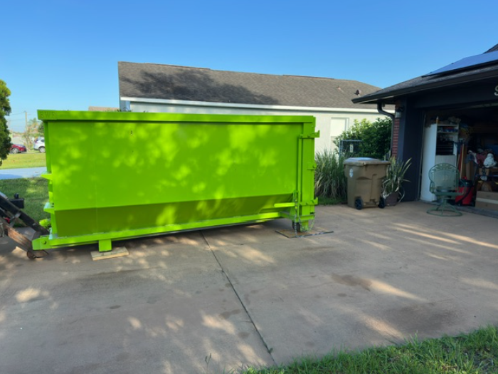 Green 16-yard roll-off dumpster placed on a residential driveway.
