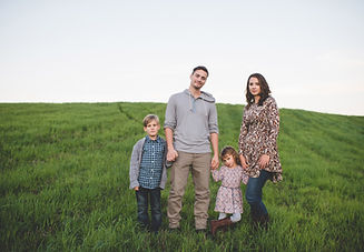 A family posing for a picture in a grassy meadow.