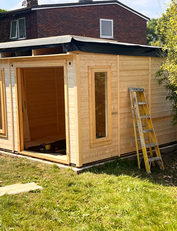 Completed timber garden office with open door and step ladder in residential Wimbledon garden by PK Decorating