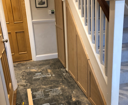 Under-stairs storage with natural wood door being fitted during staircase renovation by PK Decorating Wimbledon