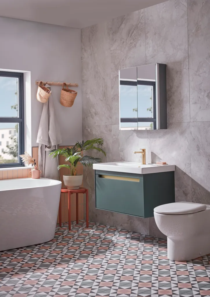 A modern bathroom with a green wall-hung vanity unit, marble-effect walls, patterned floor tiles, and a freestanding bathtub.