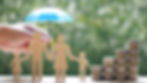 Model family with a human hand holding a tiny umbrella over their heads with a stack of coins by them 