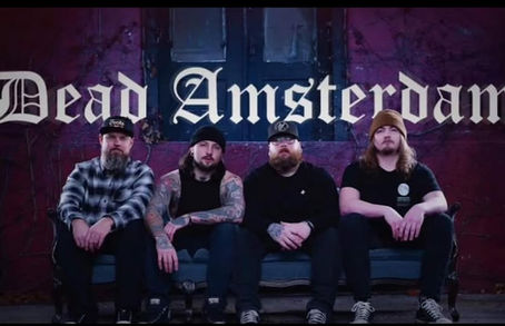 A high-energy promotional image of Dead Amsterdam, a four-member rock band from the upper Midwest. The band members—Joel Griffis, Jason Barum, Levi Riness, and Shane Loken—stand against a moody, atmospheric backdrop, exuding a raw, rebellious rock presence. Dressed in dark, edgy attire, they embody the gritty, blues-infused hard rock sound they are known for. The image captures their intense energy and camaraderie, reflecting the bold spirit of their latest single, “SuperNova
