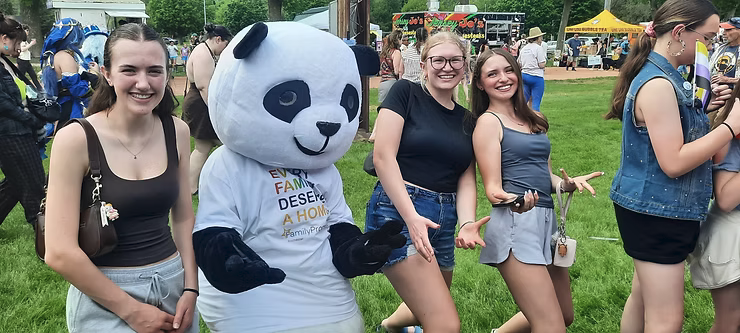 A panda mascot posing with smiling people