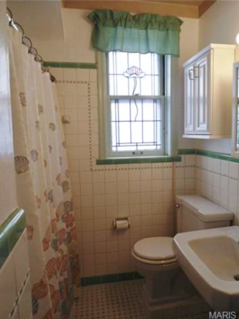 An ugly vintage bathroom with a flowered shower curtain and green ruffled window topper.