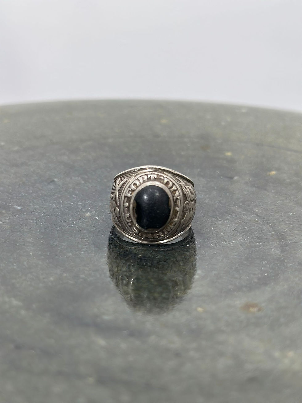 Thumbnail: A zoomed out view of the 'face' of a WW2 US Tailor Made US Army Sterling Silver Ring featuring an oval black stone set in the centre. 