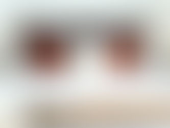 Cozy bedroom with a neatly made bed, layered pillows, and two wooden lamps. A book lies open on a wooden bench at the foot of the bed.