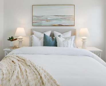 Beautiful bedroom setting showing linens, side tables, lamps and artwork