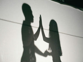 Schatten zweier Menschen, die sich gegenüberstehen und ihre Hände berühren, als Symbol für Nähe und Verbindung
