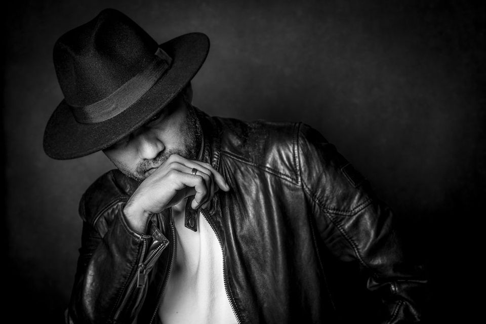 Sesja meska w Krakowie czarno-biala — portret mężczyzny w kapeluszu i skórzanej kurtce, studio Kraków