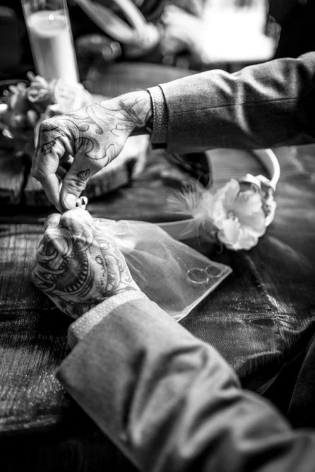 7. Fotografia ślubna czarno-biała — obrączki ślubne i tatuowane dłonie, zdjęcie detalu