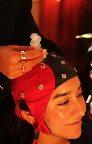 Person with a braincap on as clinician inserts syringe with gel into cap sites