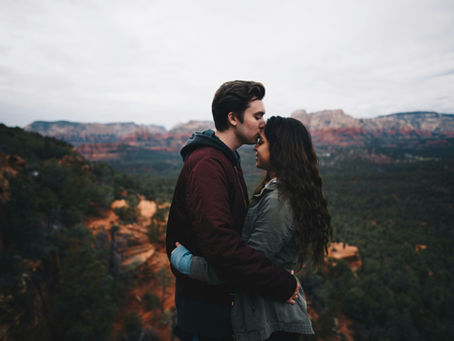 a couple kissing and hugging on a mountain top