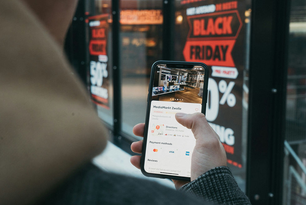 A person with a smartphone watching a store with the writing of Black Friday on it