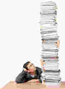 Human Resources Manager betrachtet einen riesigen Stapel von Lebensläufen.
