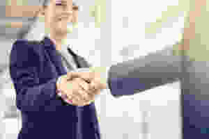A businesswoman arrives at her job interview and shakes hands with the hiring manager.