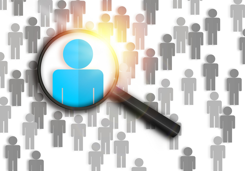 A magnifying glass highlights the perfect job candidate in a crowd.