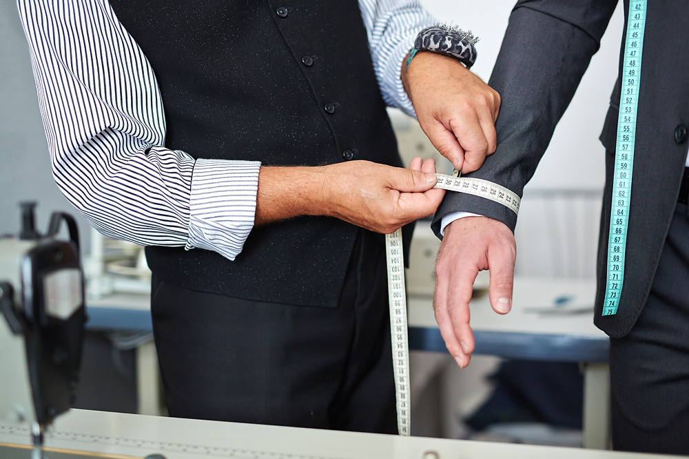 A tailor measures the arm of a businessman to make sure he has the perfect fitting suit.