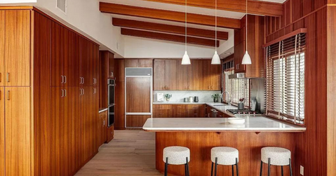 Los Feliz California home with restored midcentury modern wood kitchen featuring flat panel cabinets, white quartz countertops and unique elements like ceiling beams.