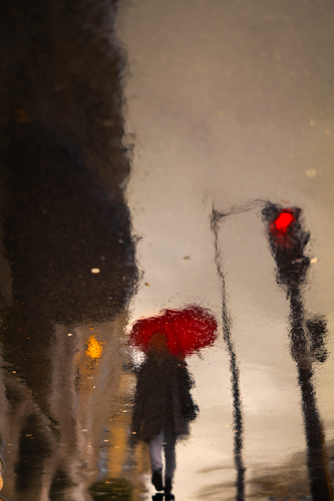 A captivating street scene featuring a single red umbrella providing a splash of color in a monochromatic urban environment.