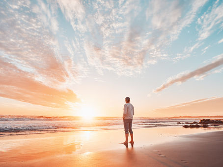 a man on the beach at sunrise in deep contemplation