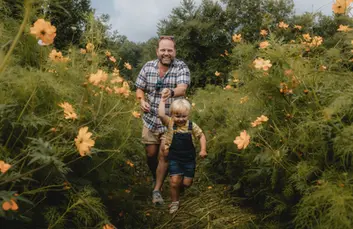 Happy father and son running through cosmos flowers