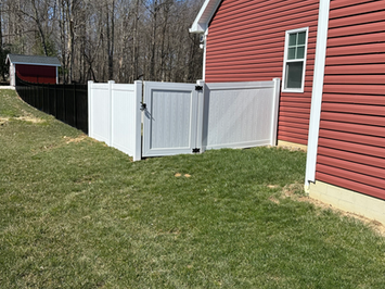 White vinyl fence gate beside red barn