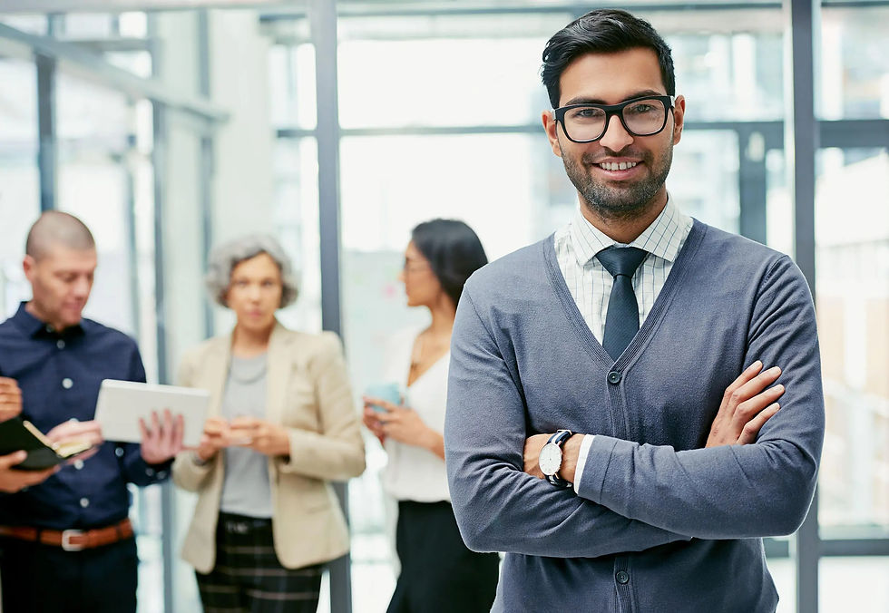 Smiling man in glasses with colleagues in modern office setting.