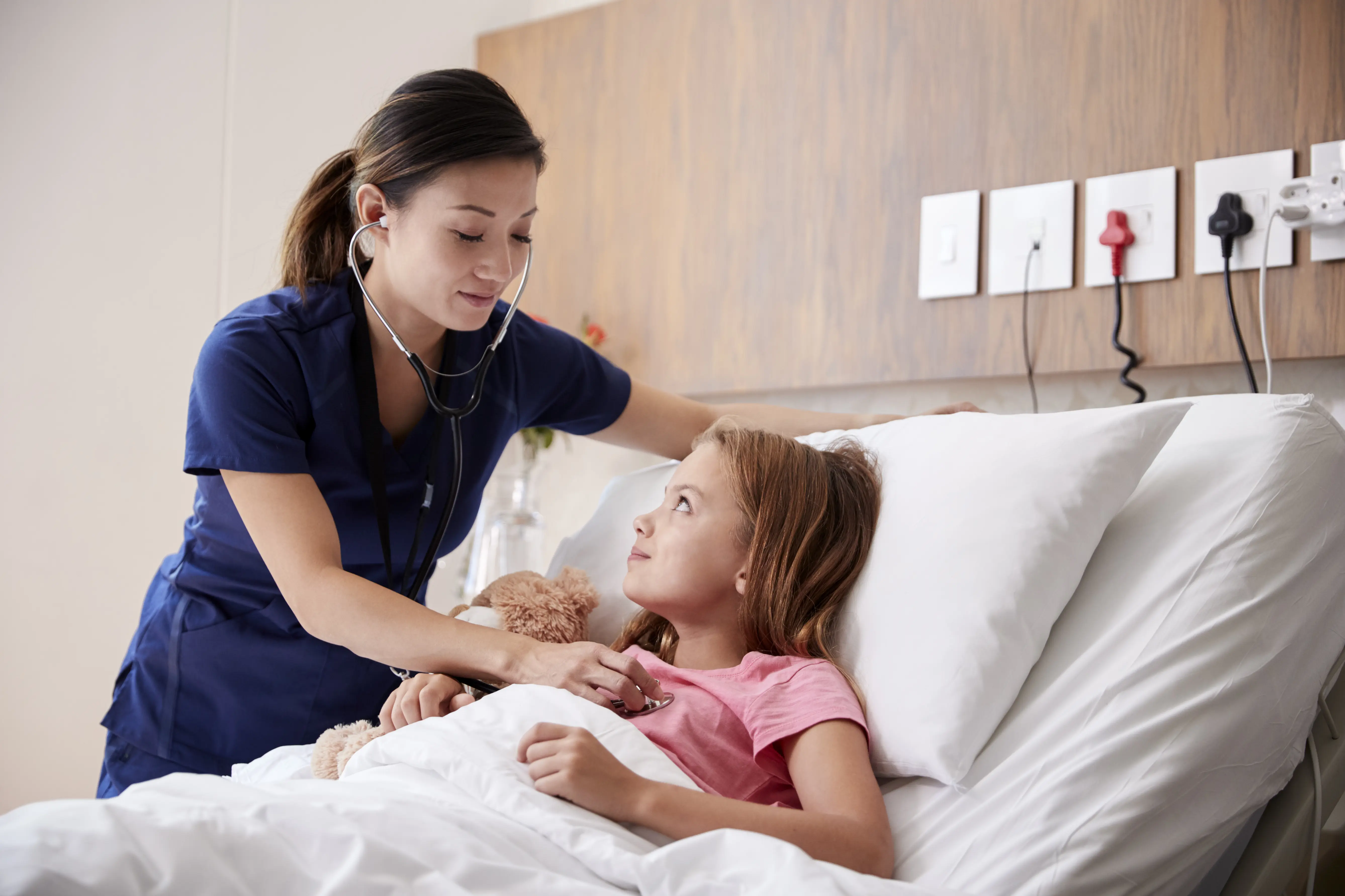Nurse taking care of young girl in hospital