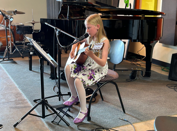 Girl playing acoustic guitar during music lesson