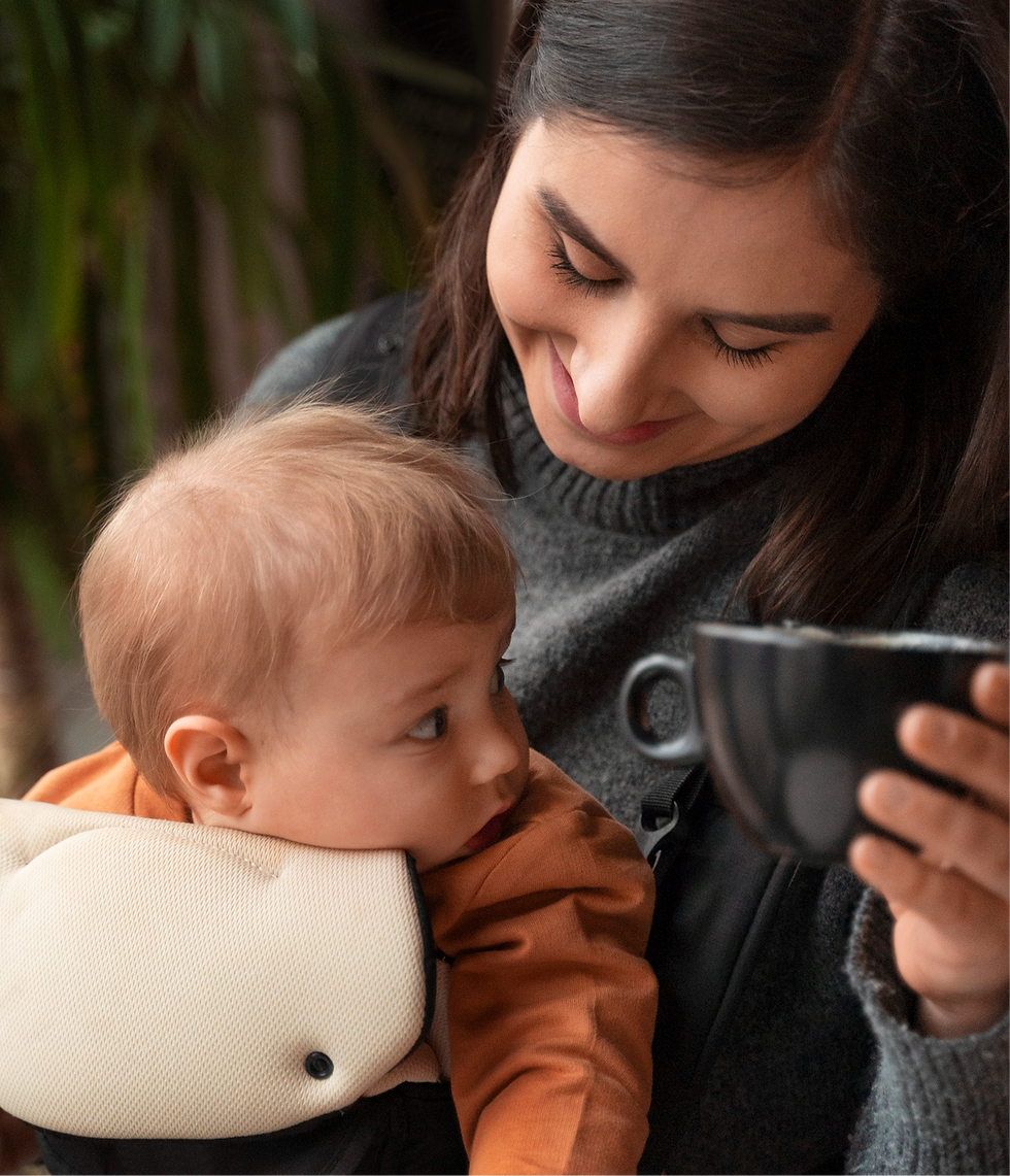 Smiling mother holding baby, enjoying coffee