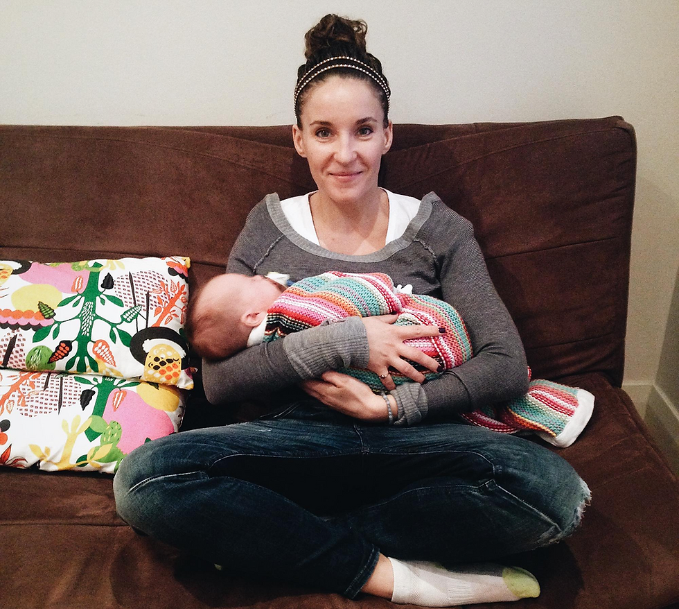Mother gently cradling newborn baby on sofa