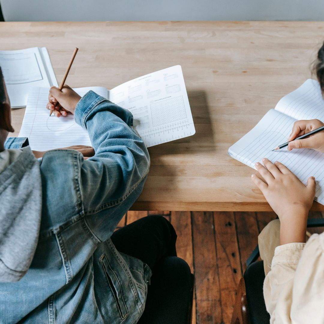 Two children at desk working on classroom tasks