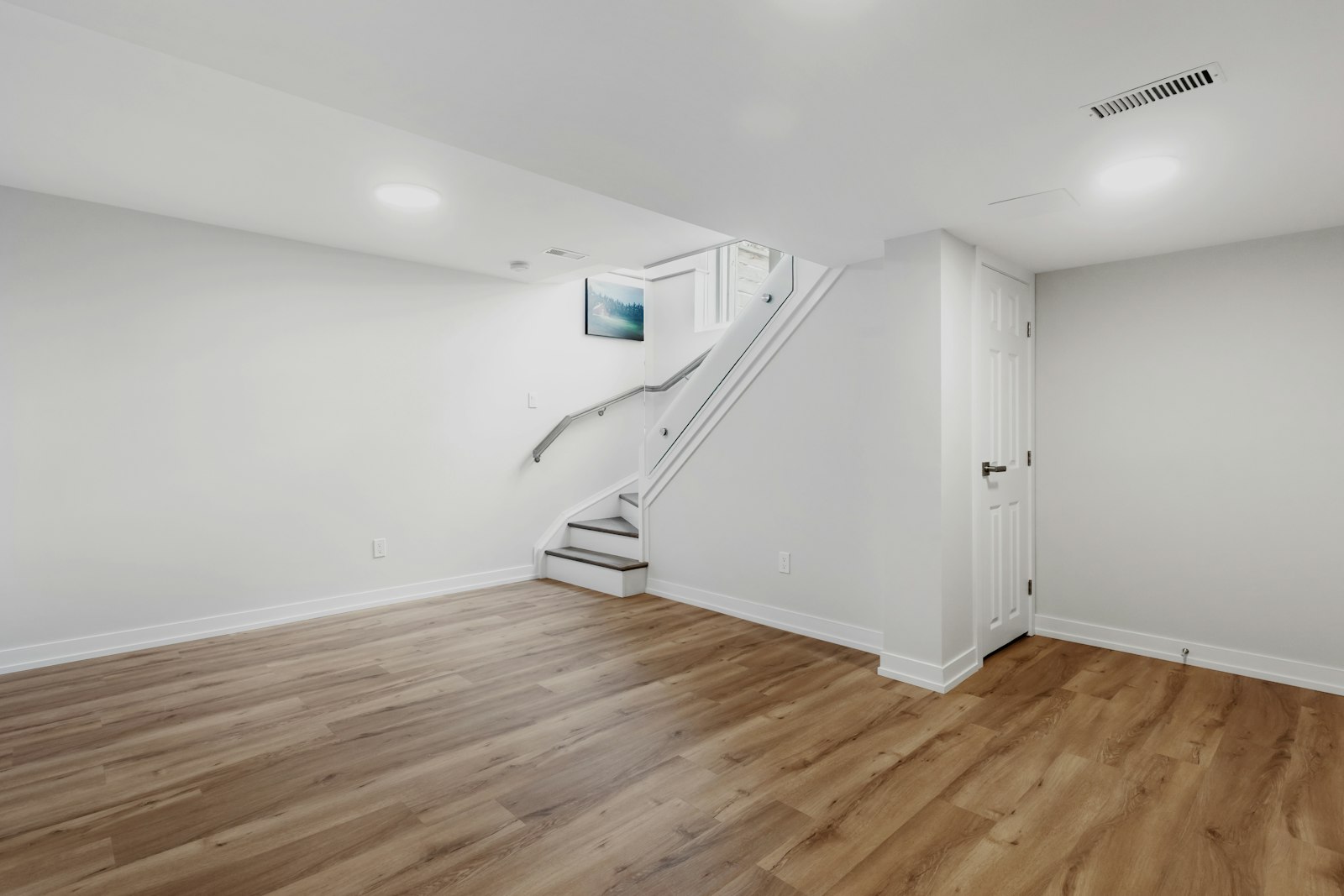 Finished basement with wood-look flooring and staircase