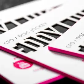 Close-up of premium white business cards featuring vibrant magenta painted edges and bold, minimalist black typography.