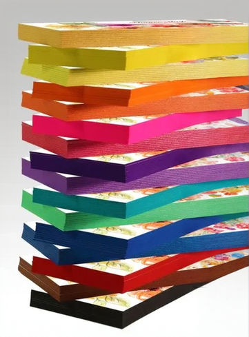 A tall stack of painted edge business cards with each card a different bright color, showing the colored edges, including red, orange, yellow, green, blue, purple, and black.