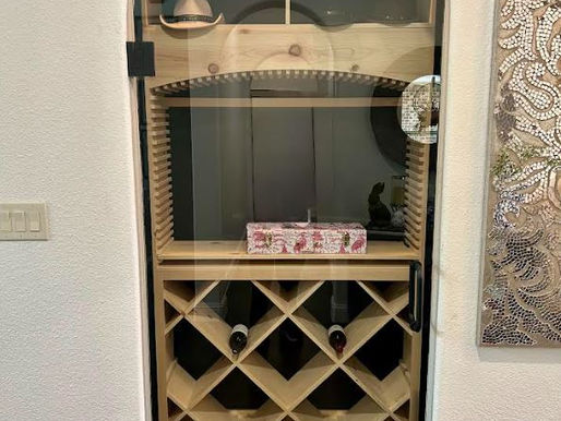 Closed custom arched glass door for a wine cellar featuring matte black hardware and wood shelving. in McKinney, Texas