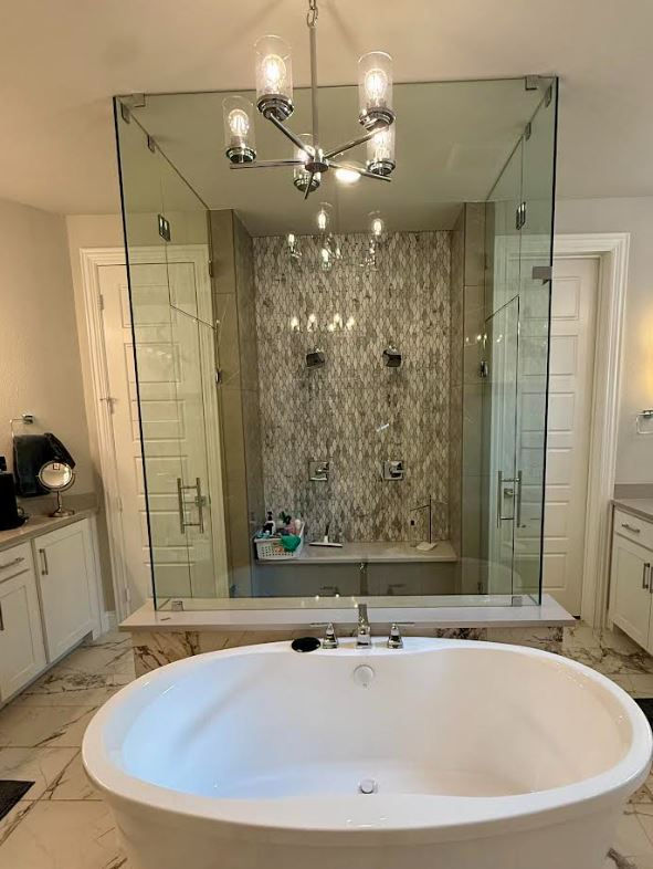 Floor-to-ceiling frameless glass steam shower enclosure positioned behind a freestanding soaking tub in McKinney, Texas