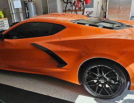 Orange Chevrolet Corvette with tinted side windows parked in a garage